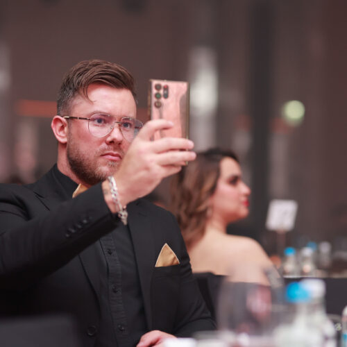 Man in formal suit capturing moments at a business event