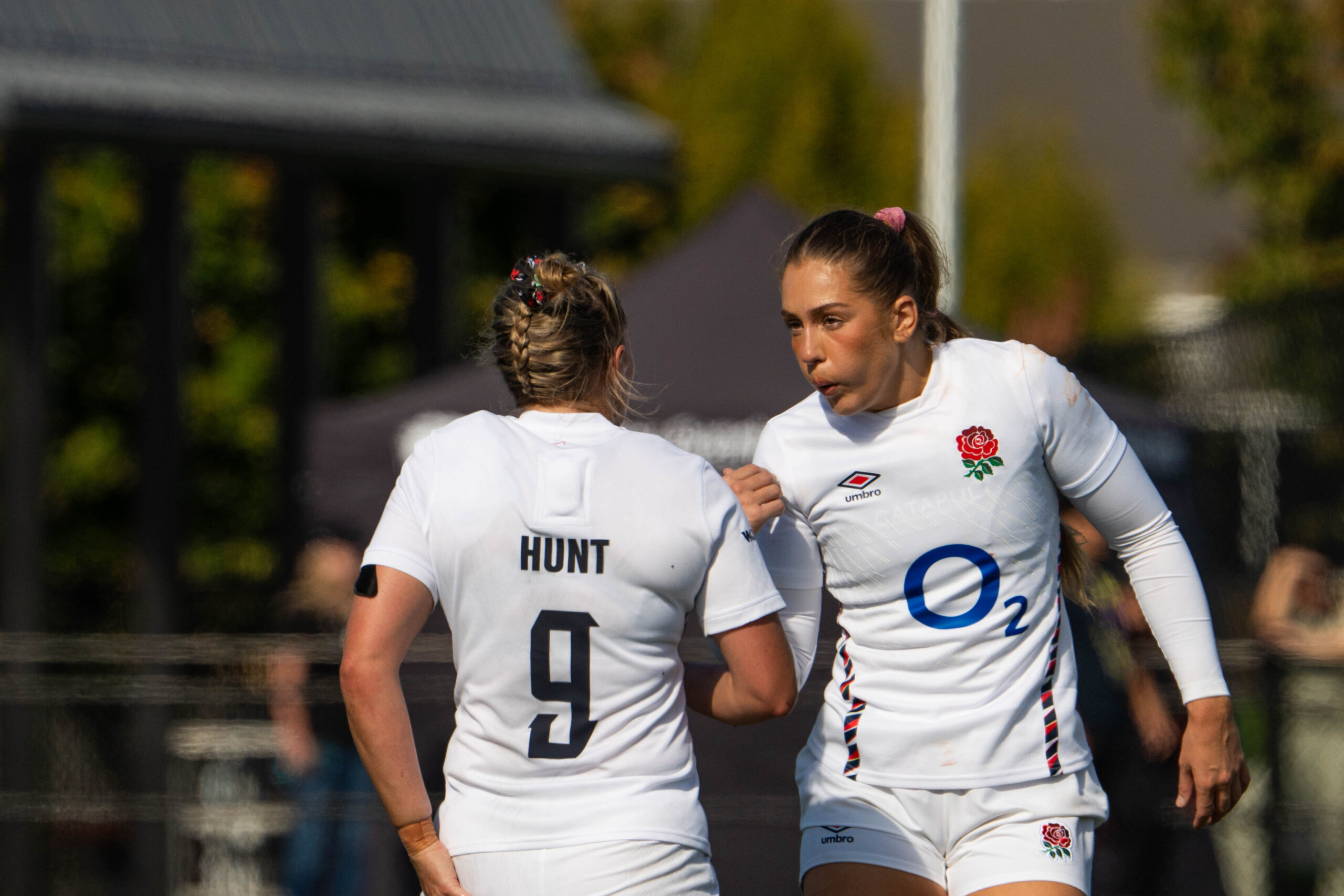 England rugby player Mo Hunt (number 9) talking to a teammate in the white Red Roses kit.