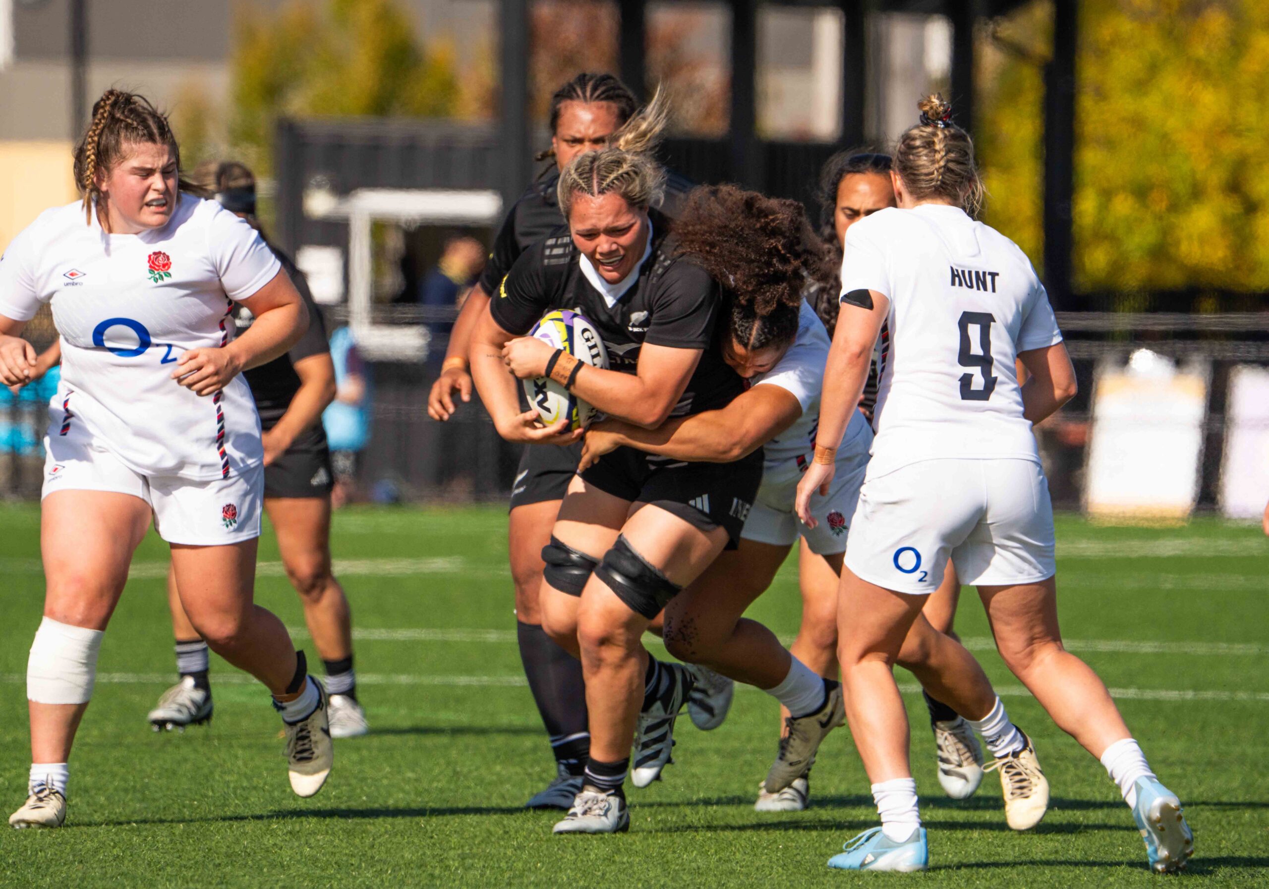 Action shot of a New Zealand rugby player breaking through an England defensive line.