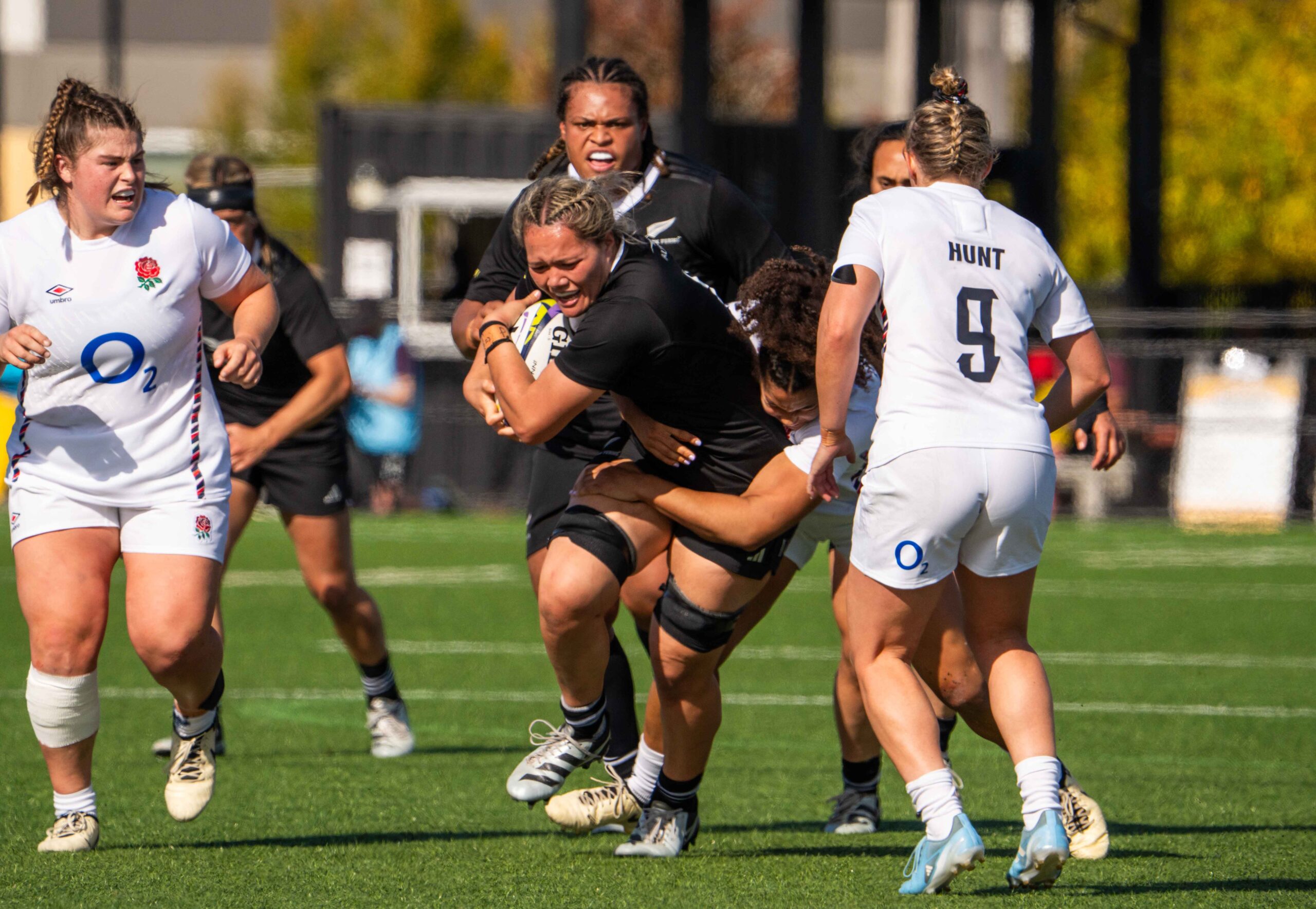 Action shot of a New Zealand rugby player breaking through an England defensive line.