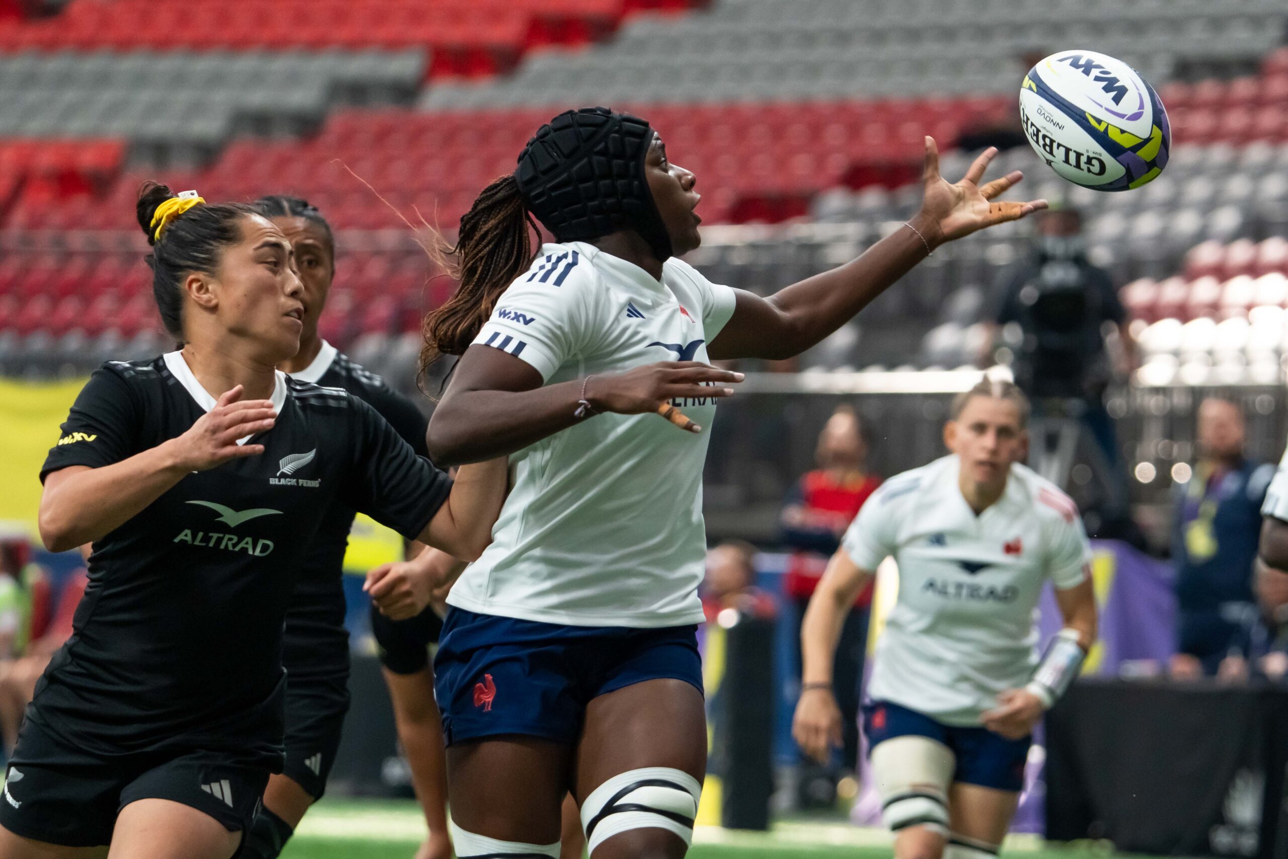 France international rugby player catching a high ball under pressure from a New Zealand Black Ferns player.