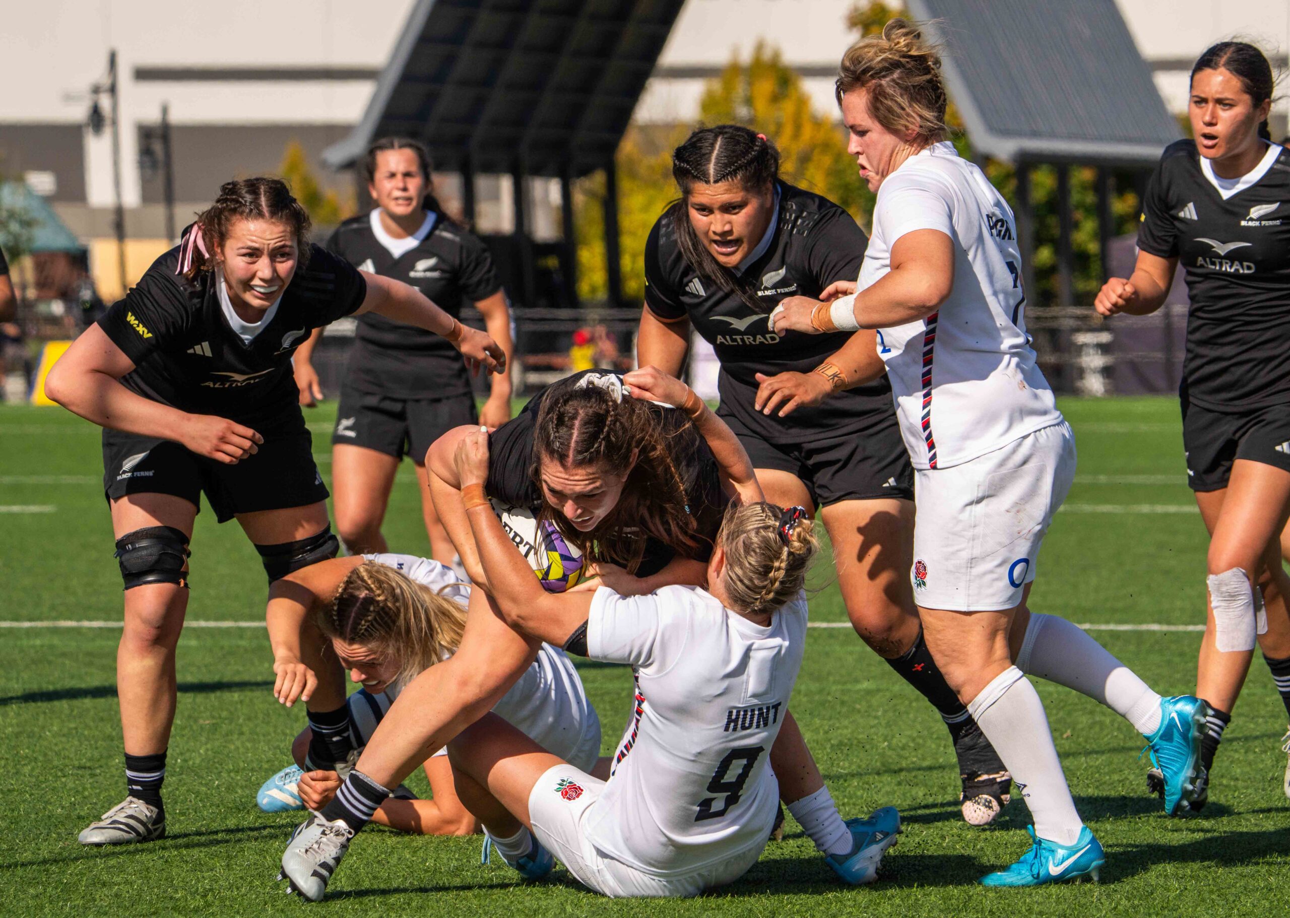 Multiple rugby players on the ground and standing during a breakdown in a match between England and New Zealand.