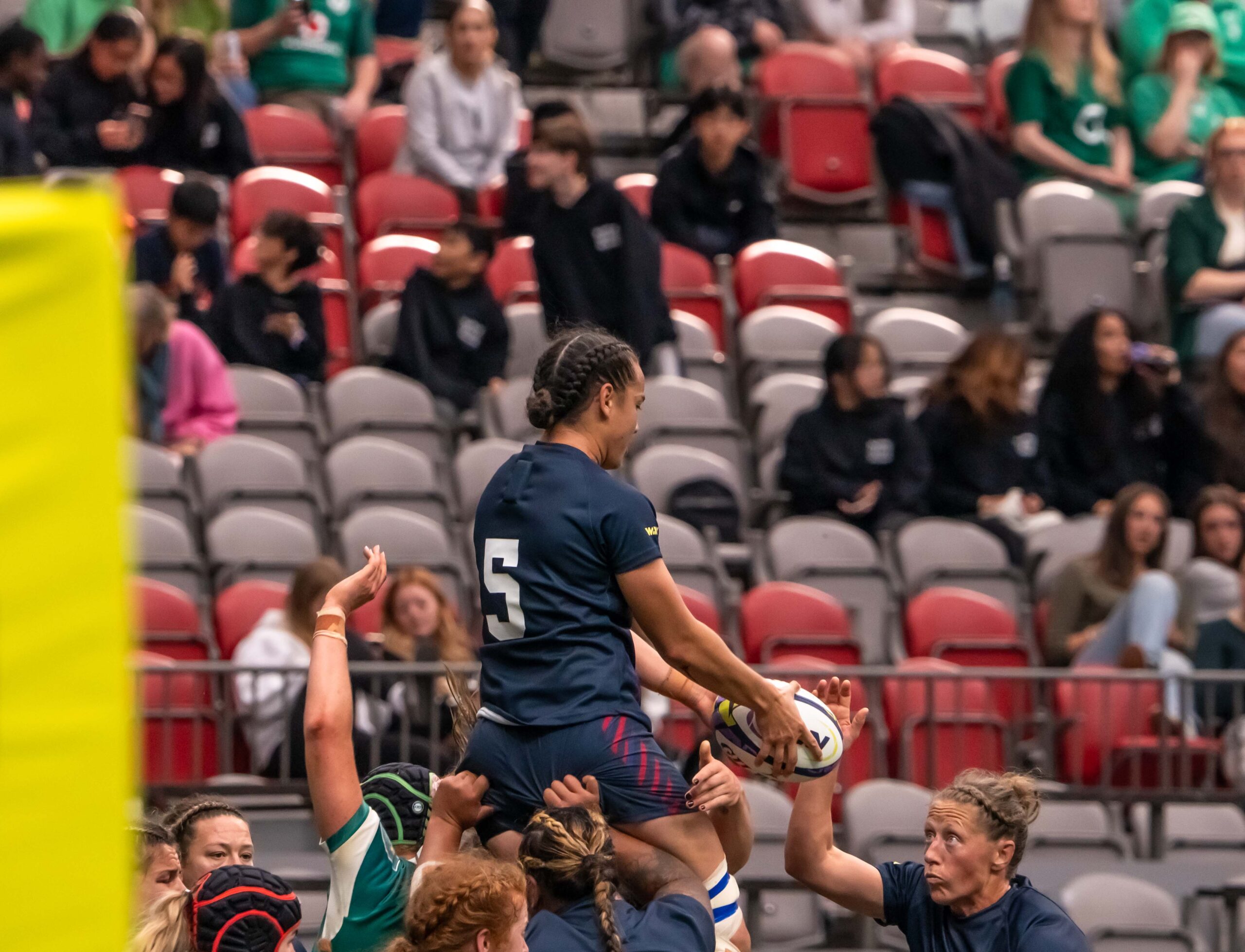 USA Rugby player jumping for the ball during a lineout in a professional women's rugby match.