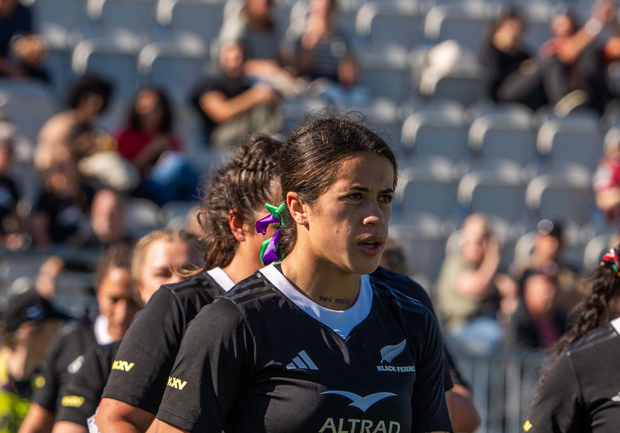 Black Ferns rugby player gripping the ball tightly while being contested by multiple England players