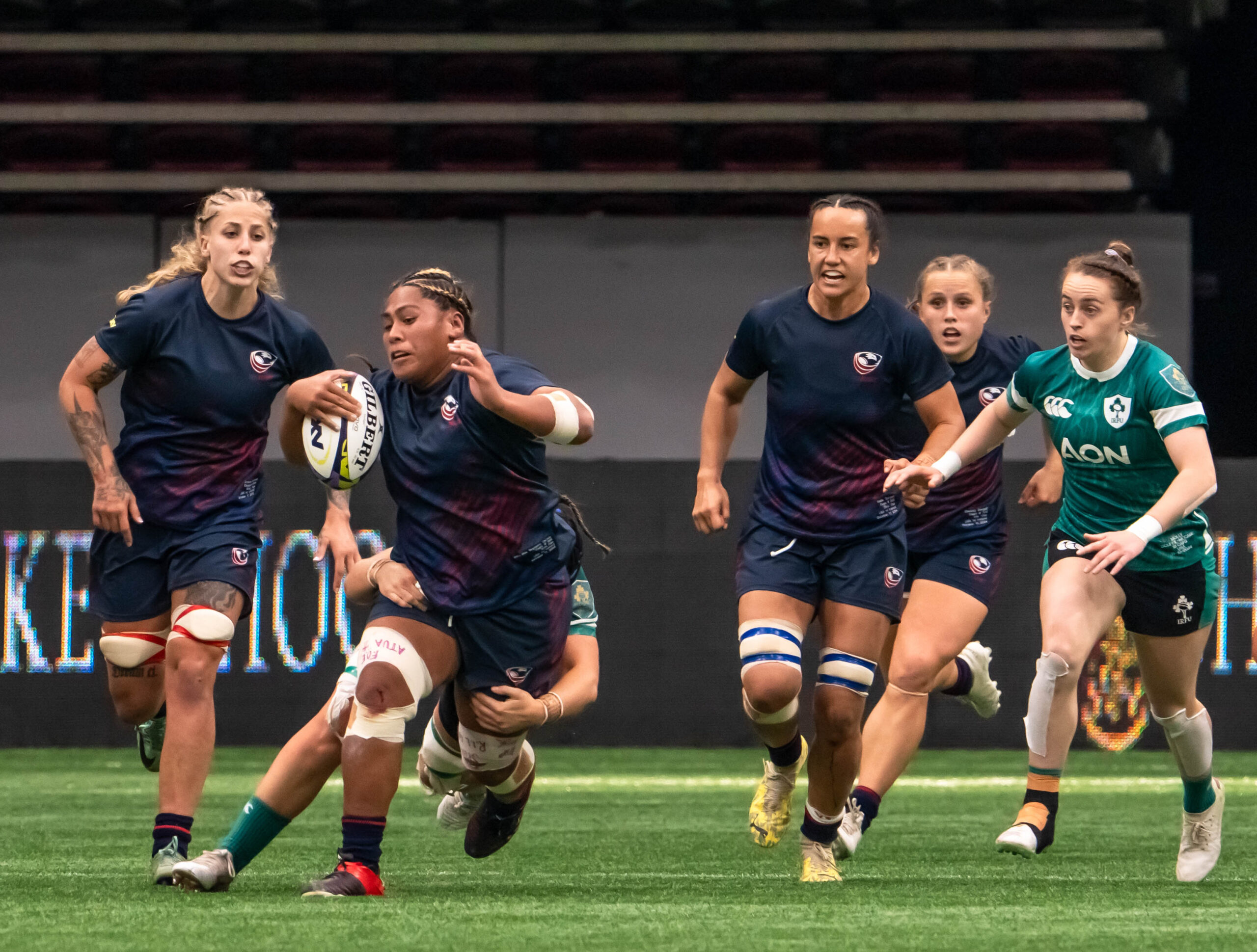 USA Rugby player sprinting with the ball against Ireland's defensive line in Dubai tournament.