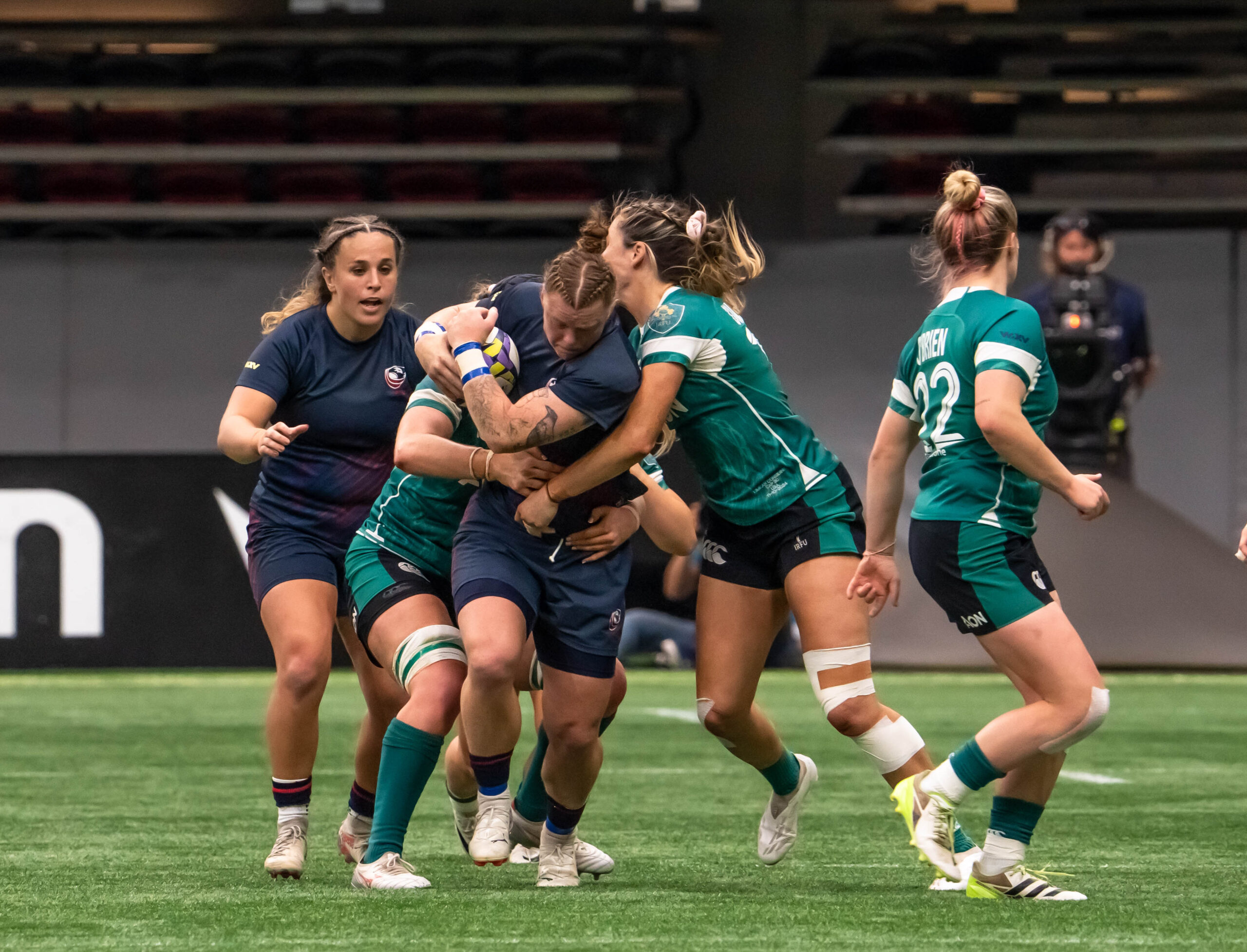 Close-up of USA Women's Rugby player being tackled by Ireland defenders during WXV 1 match.