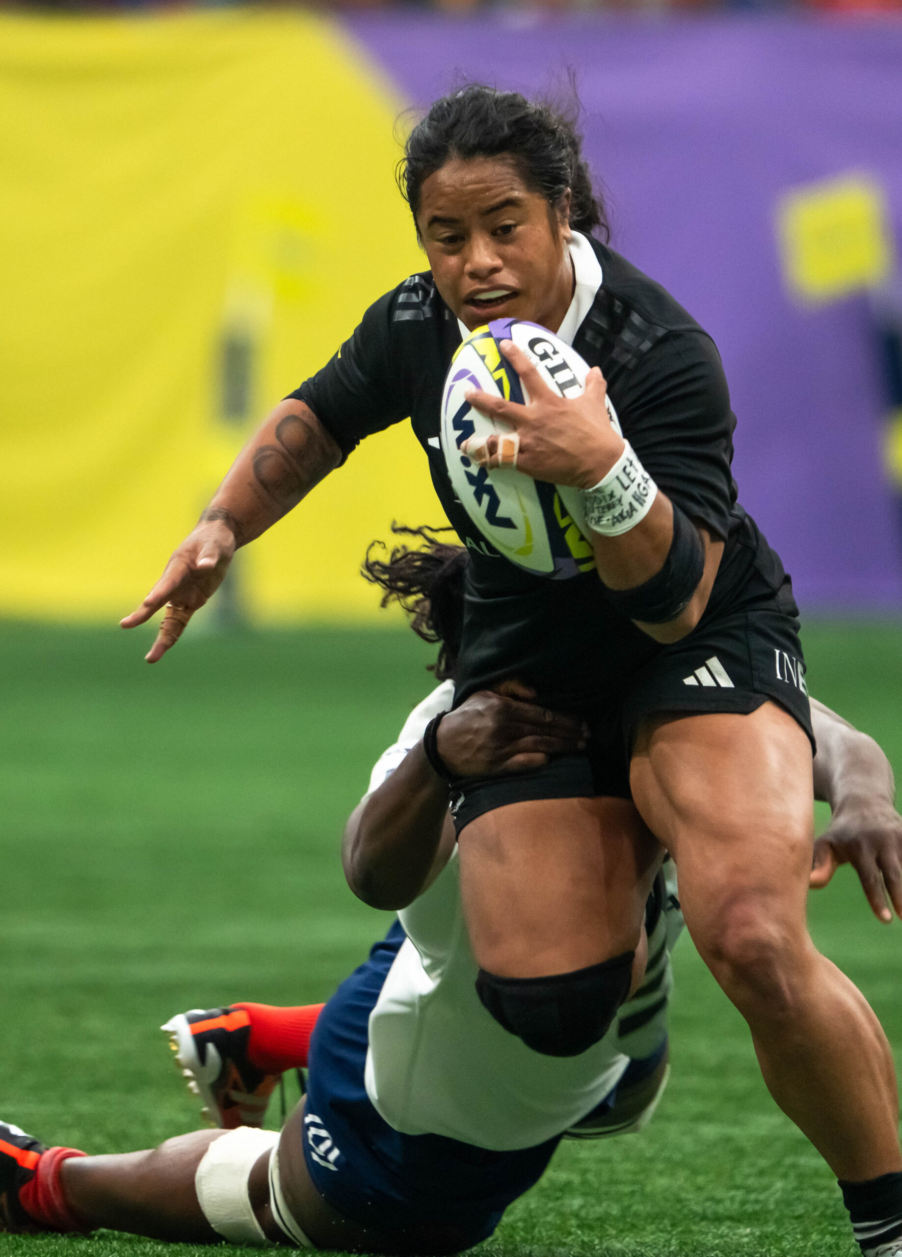 France Women's Rugby player in white jersey being tackled by three New Zealand Black Ferns players.