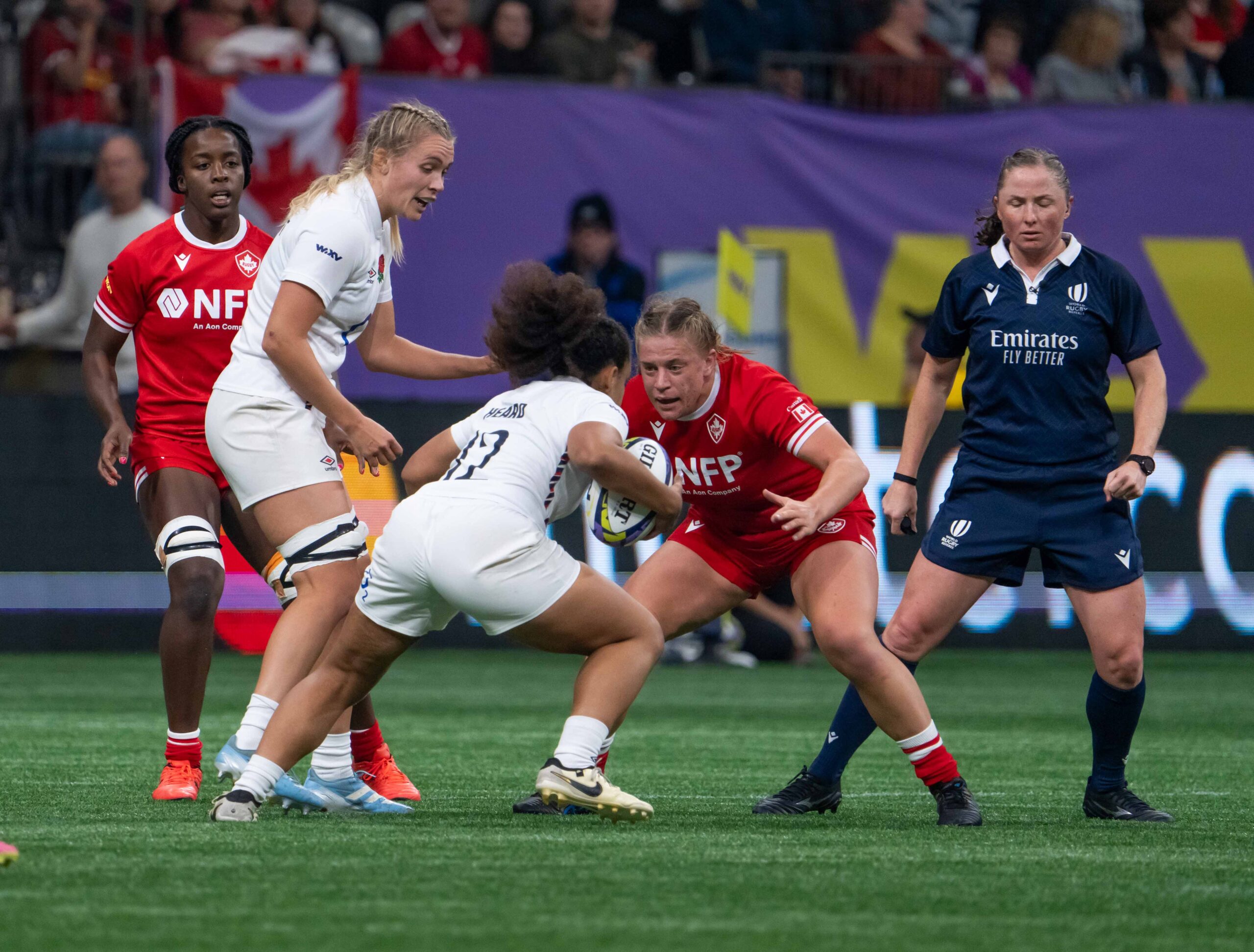 England rugby player attacking the Canadian defense with a World Rugby referee in view.