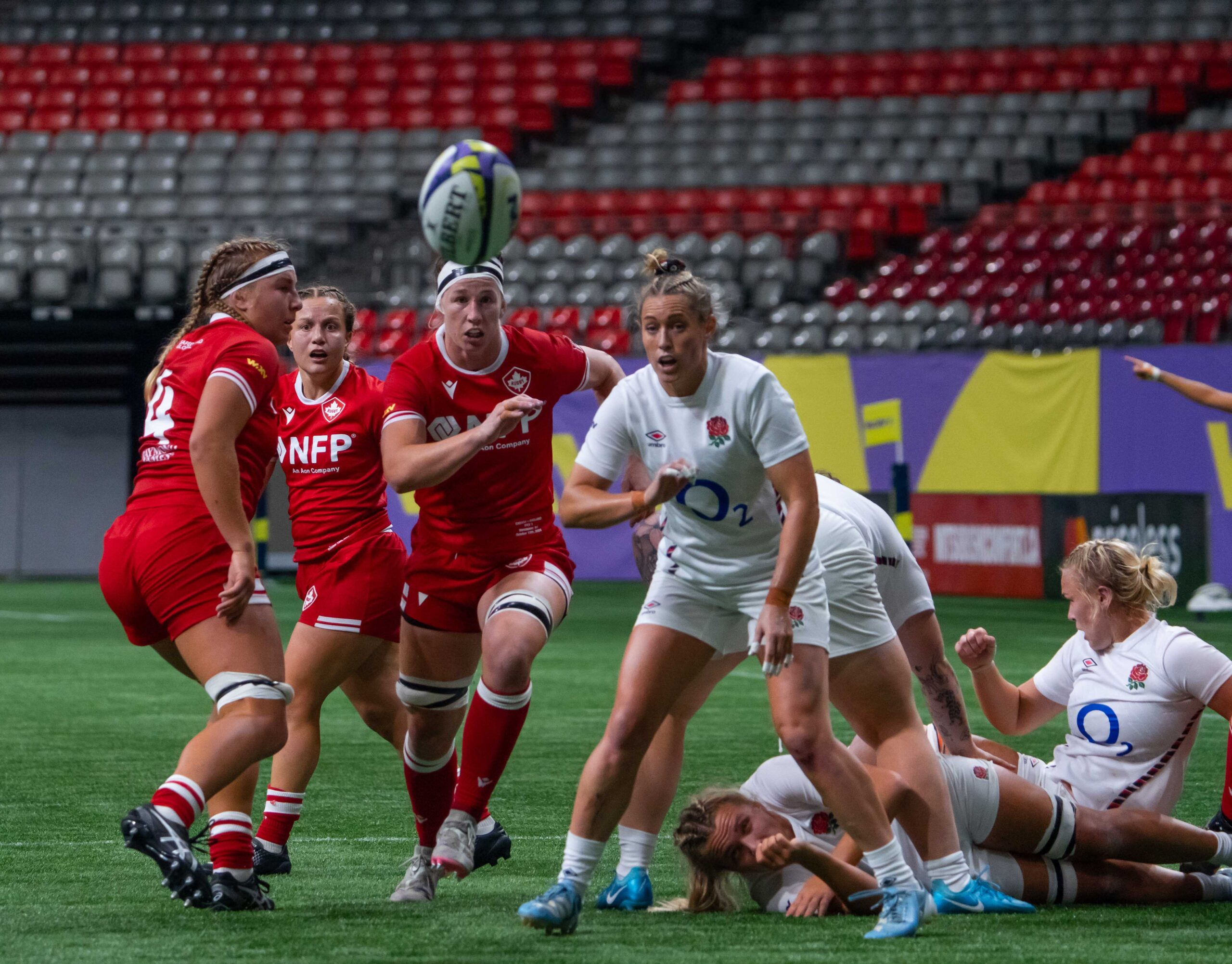 England and Canada players tracking a high ball during a WXV 1 international rugby union fixture.
