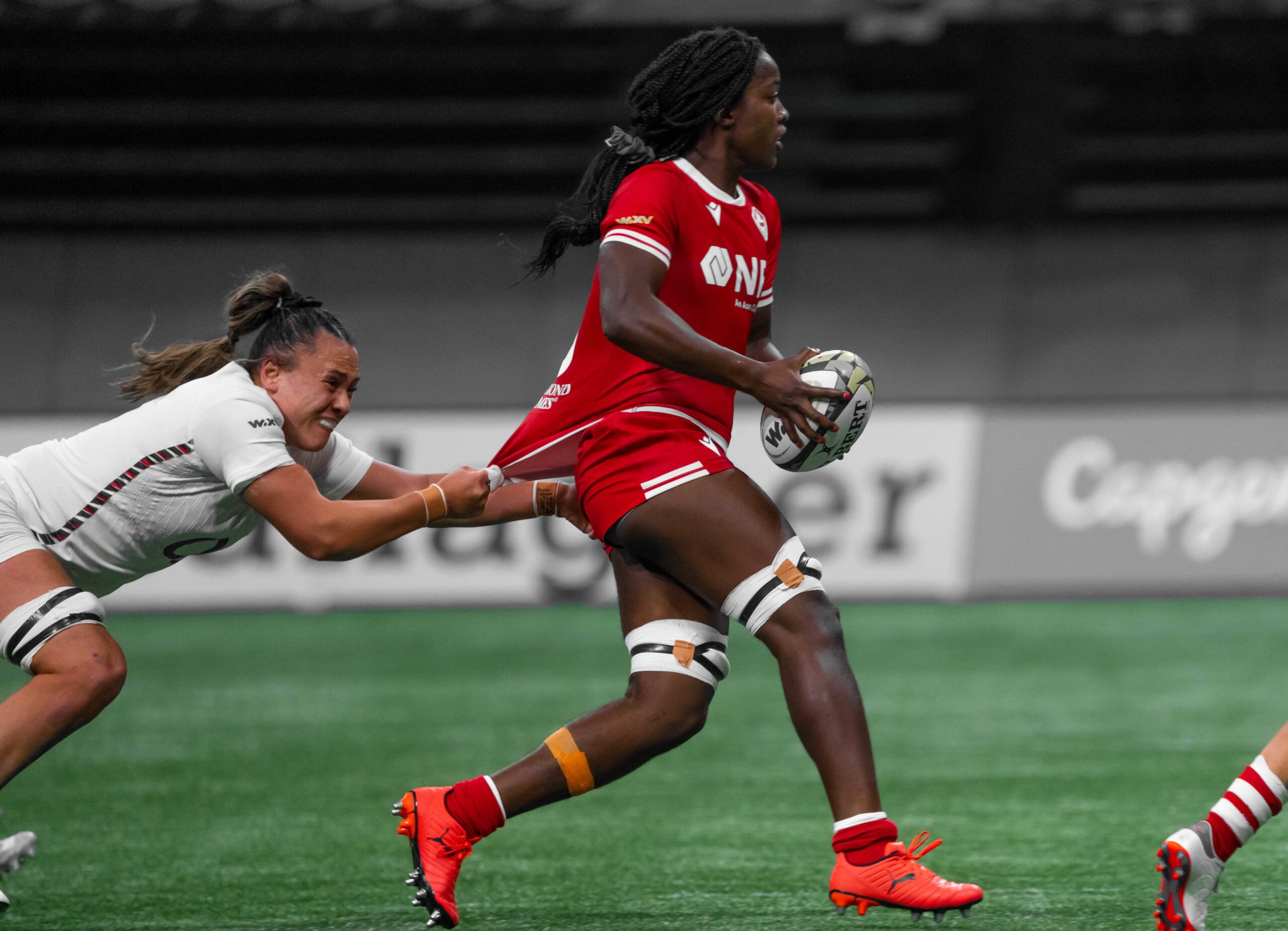 England player attempting a jersey tackle on a Canada ball carrier during a WXV 1 match.