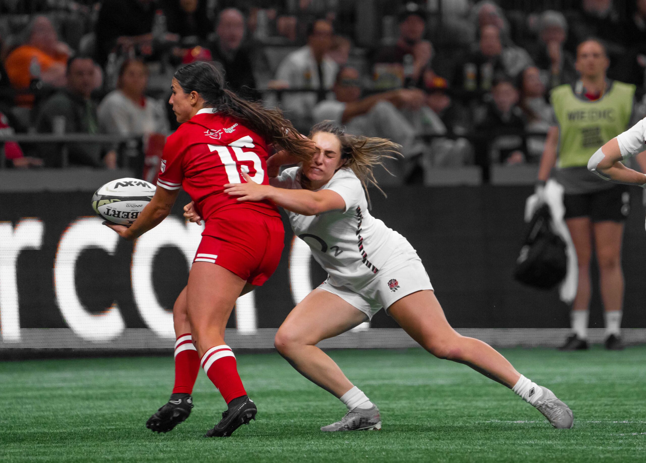 Canada's number 15 being tackled from behind by an England defender in a WXV 1 international.