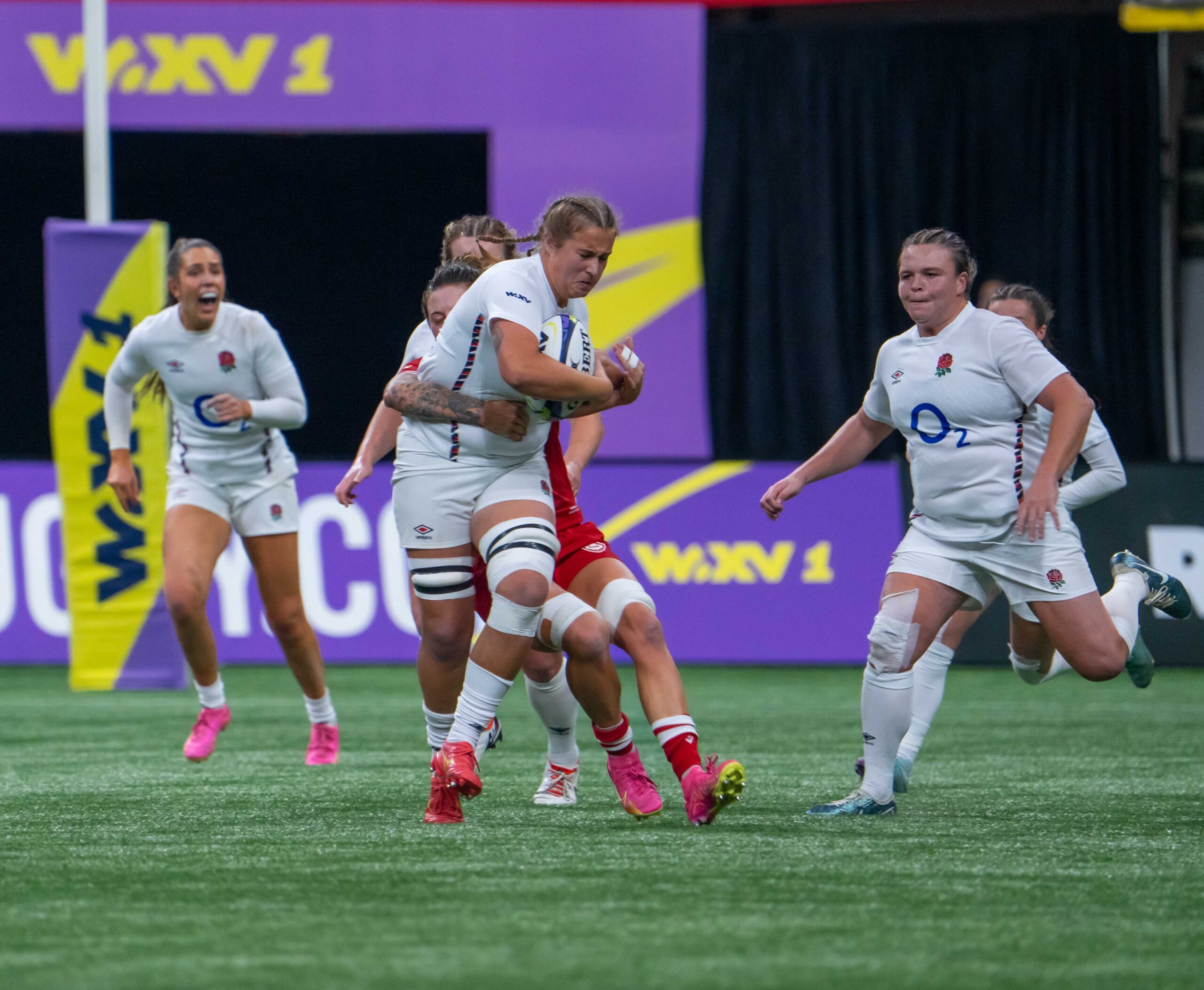 England Red Roses player carrying the ball during a high-intensity tackle against Canada in the WXV 1 tournament.