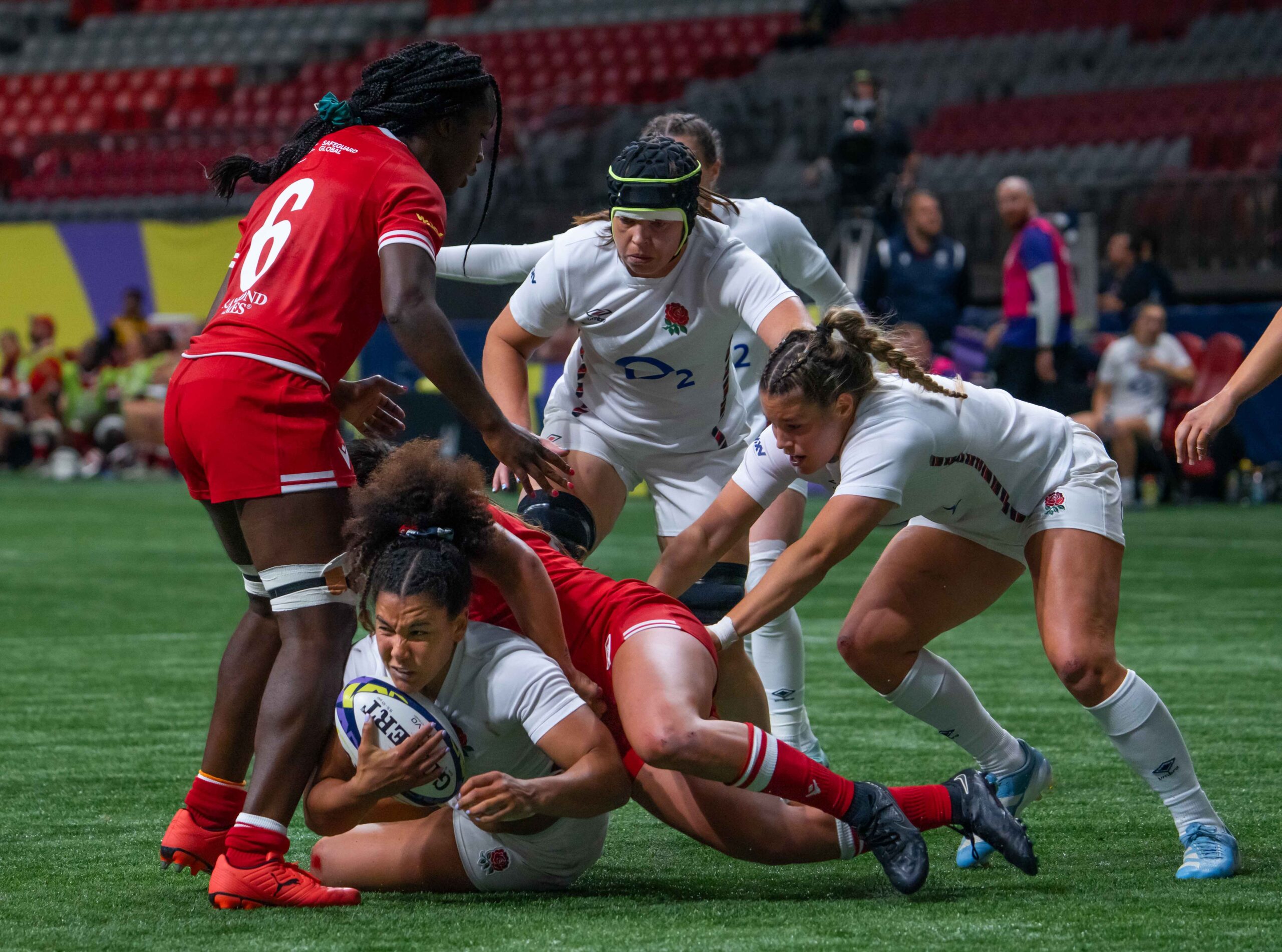 Intense breakdown action as England and Canada women's rugby players compete for possession on the ground.