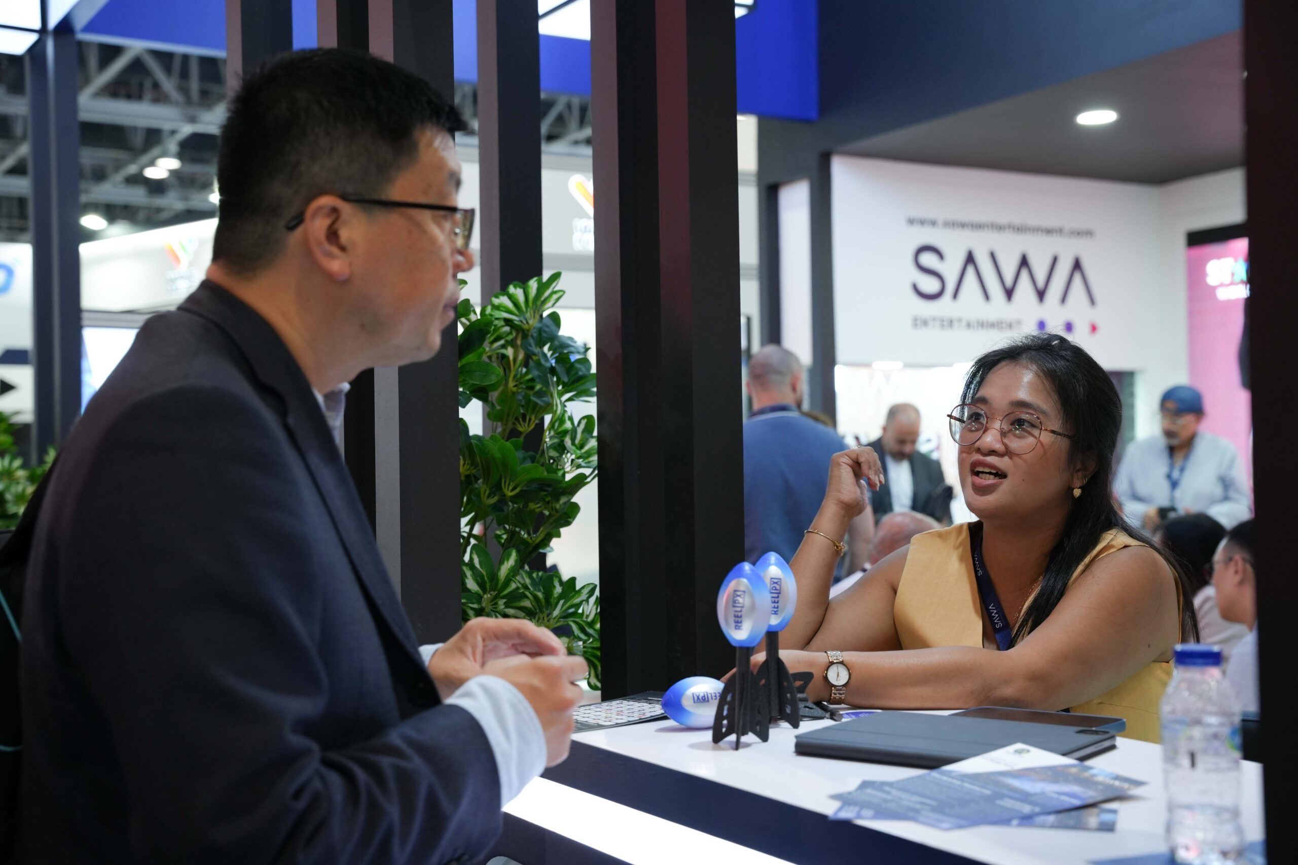 Global media professionals exchanging ideas at a trade show exhibit in Dubai.