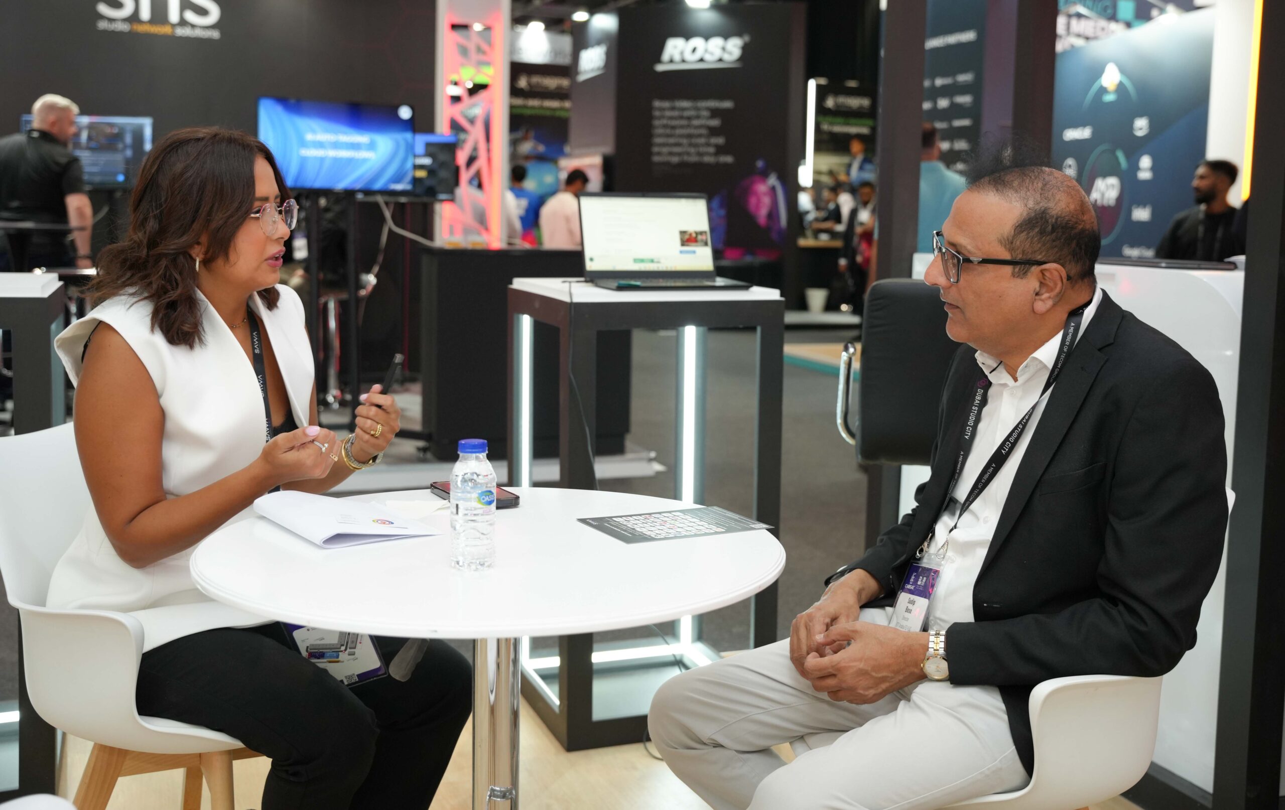 Business meeting between media executives at CABSAT 2025 in Dubai.