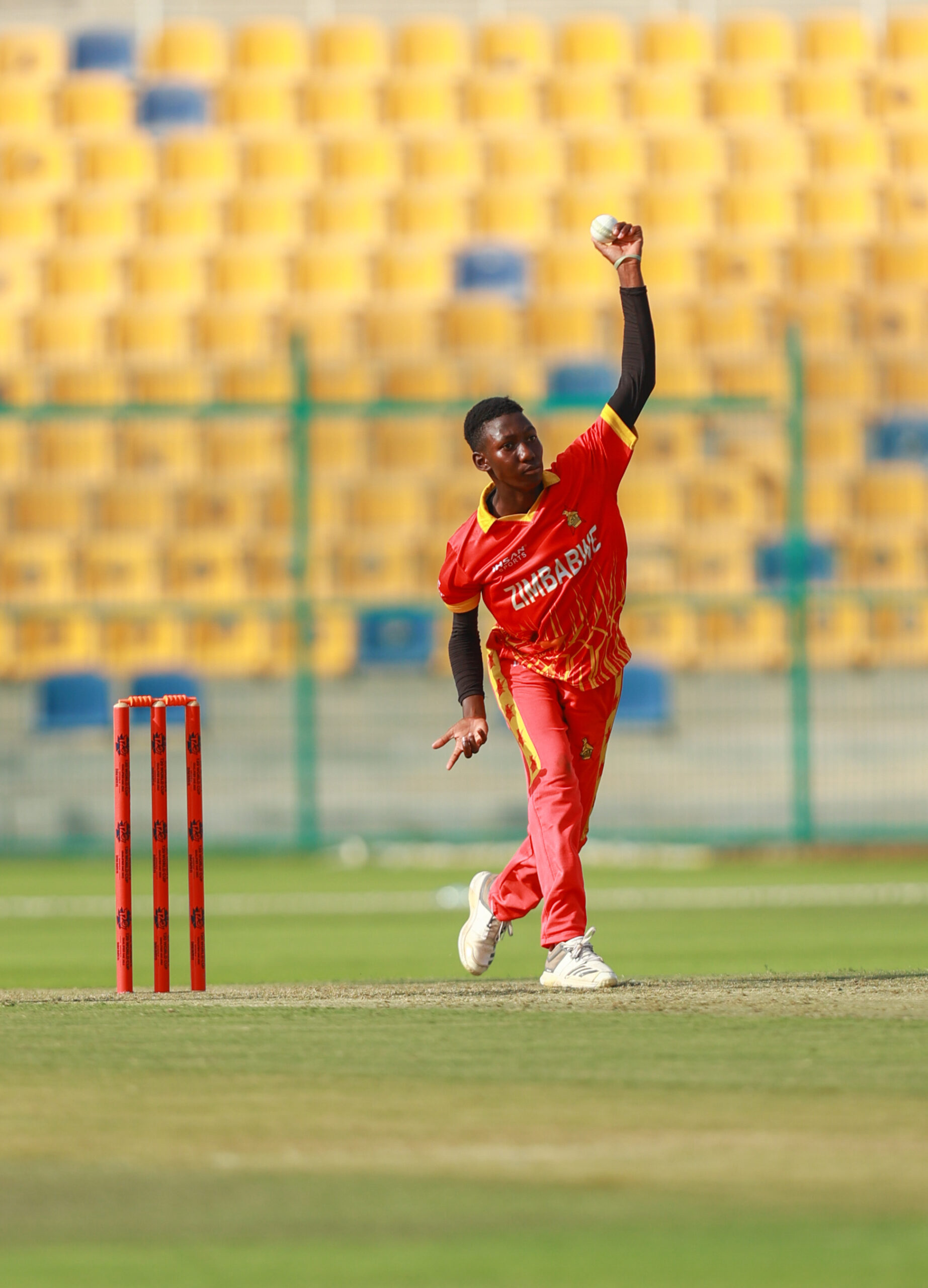 Zimbabwe women's cricket bowler in mid-action at a stadium in Dubai during an international cricket tour.