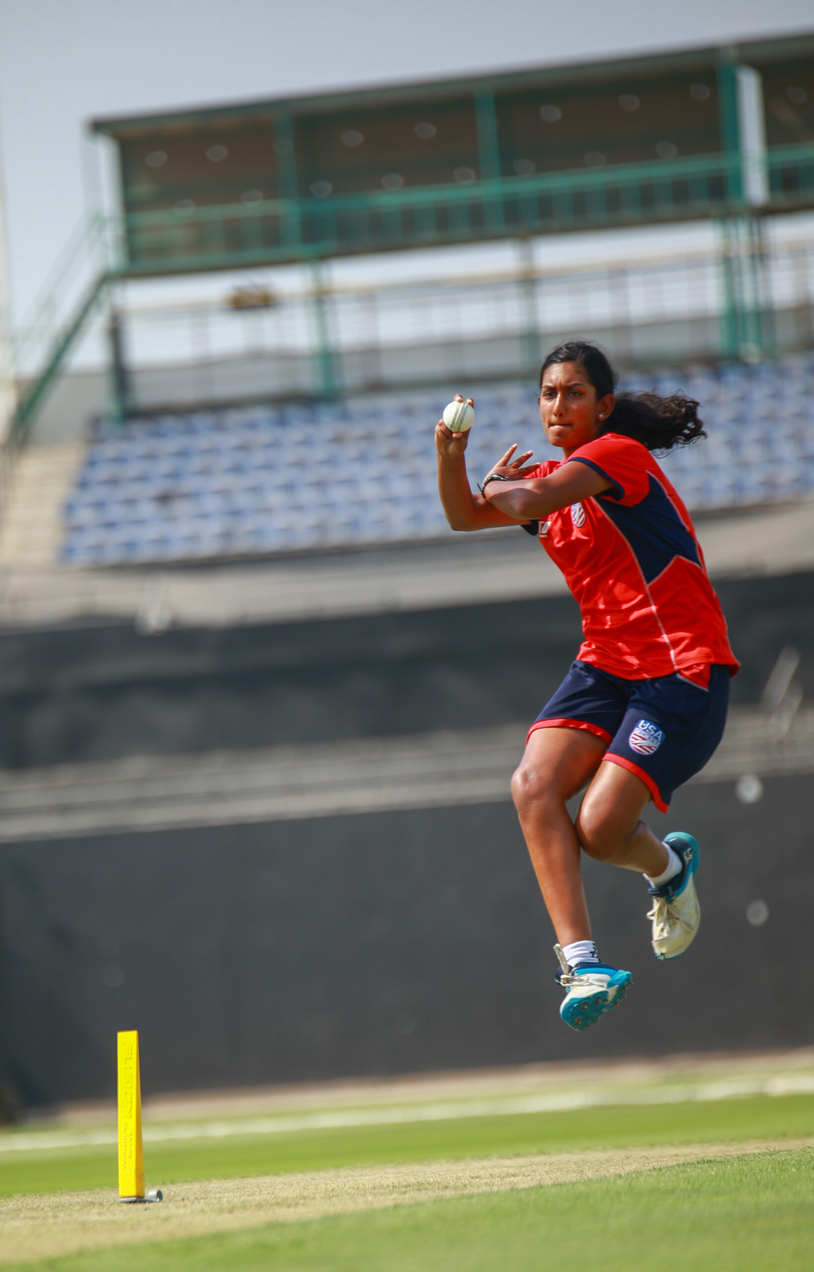 USA women's cricket team bowler in mid-air delivery during a professional match in Dubai, UAE
