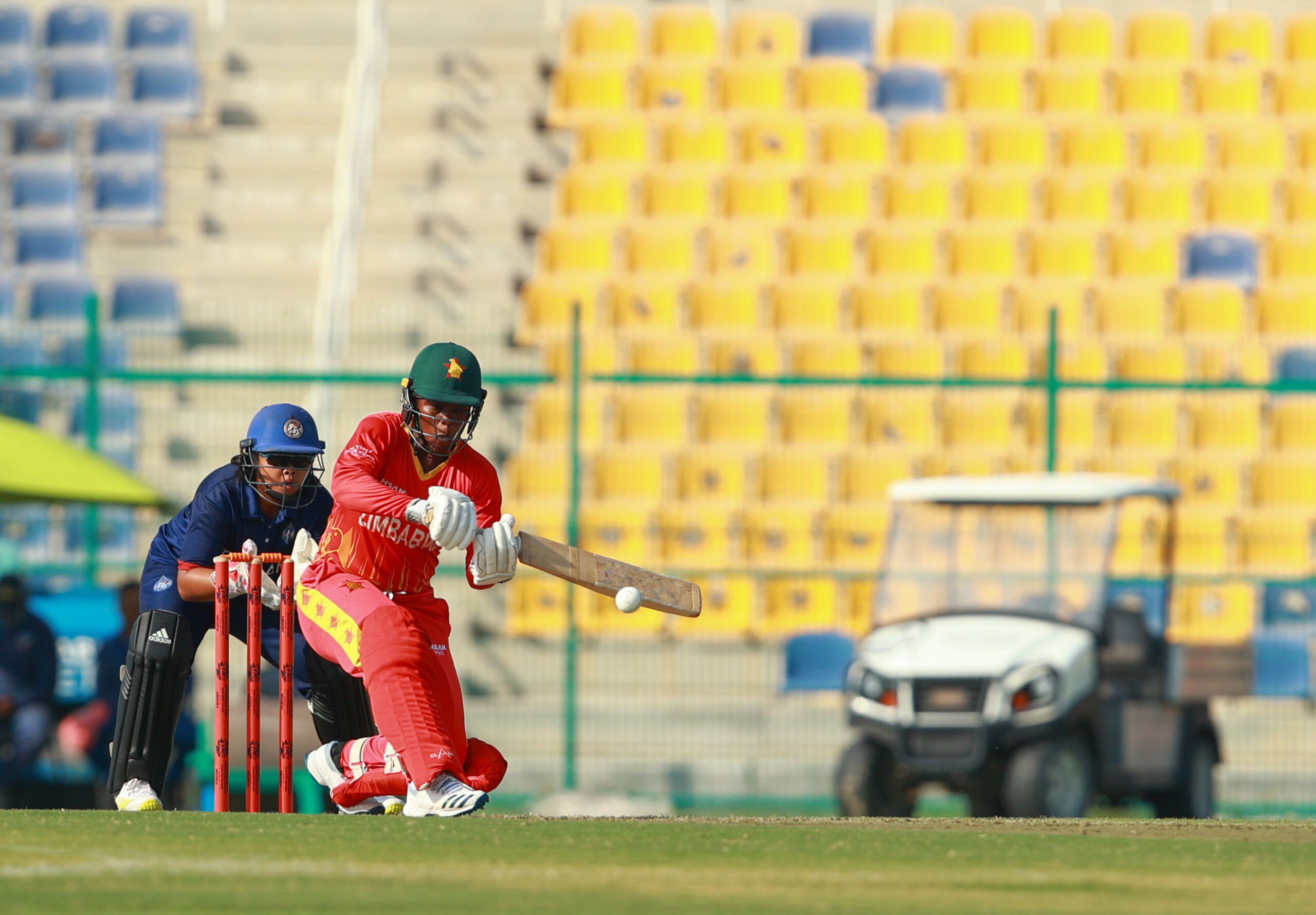 International women's cricket match in Dubai featuring Zimbabwe batter in action at the crease.