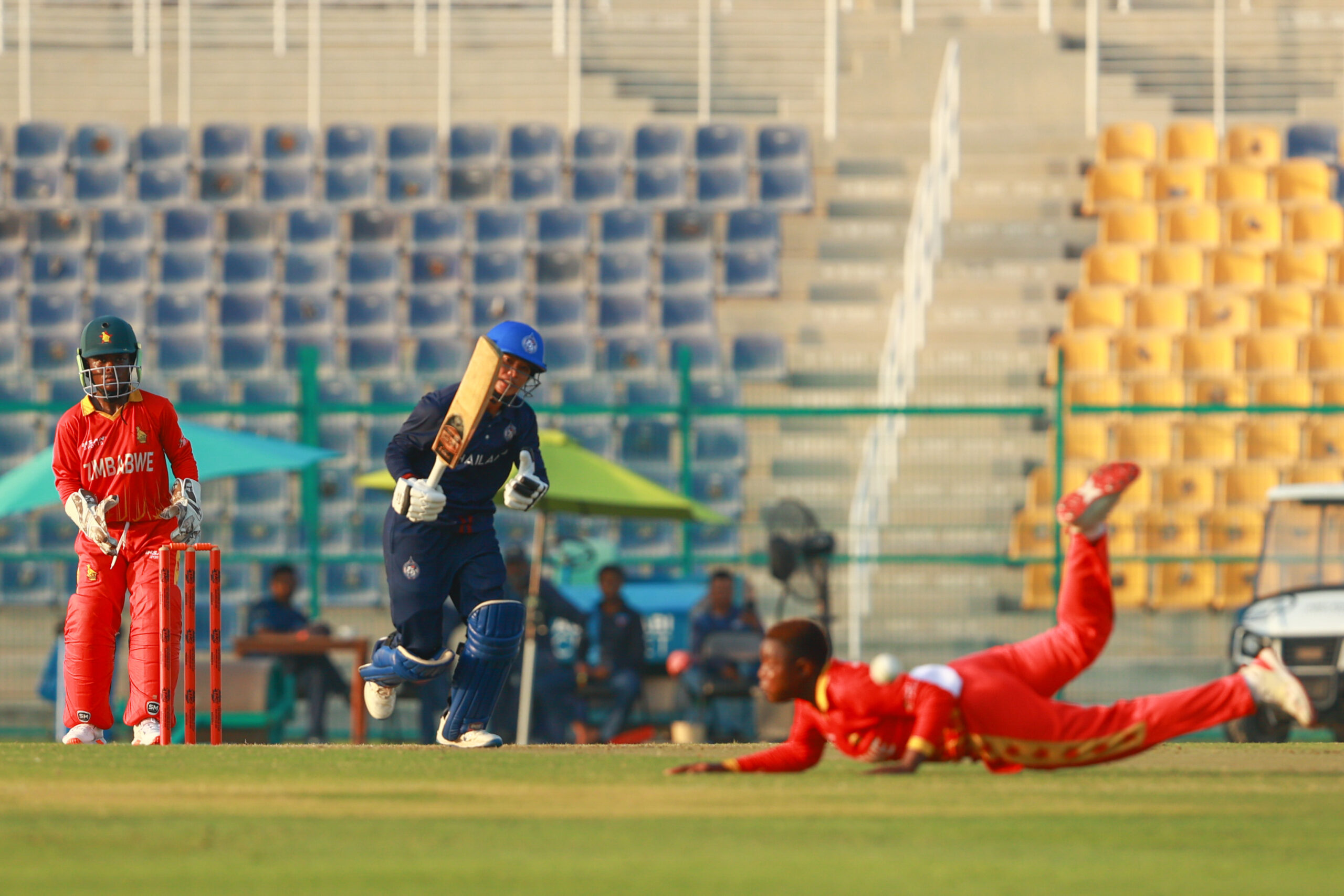 Zimbabwe fielder diving on the grass to stop a boundary during an international cricket match in Dubai.