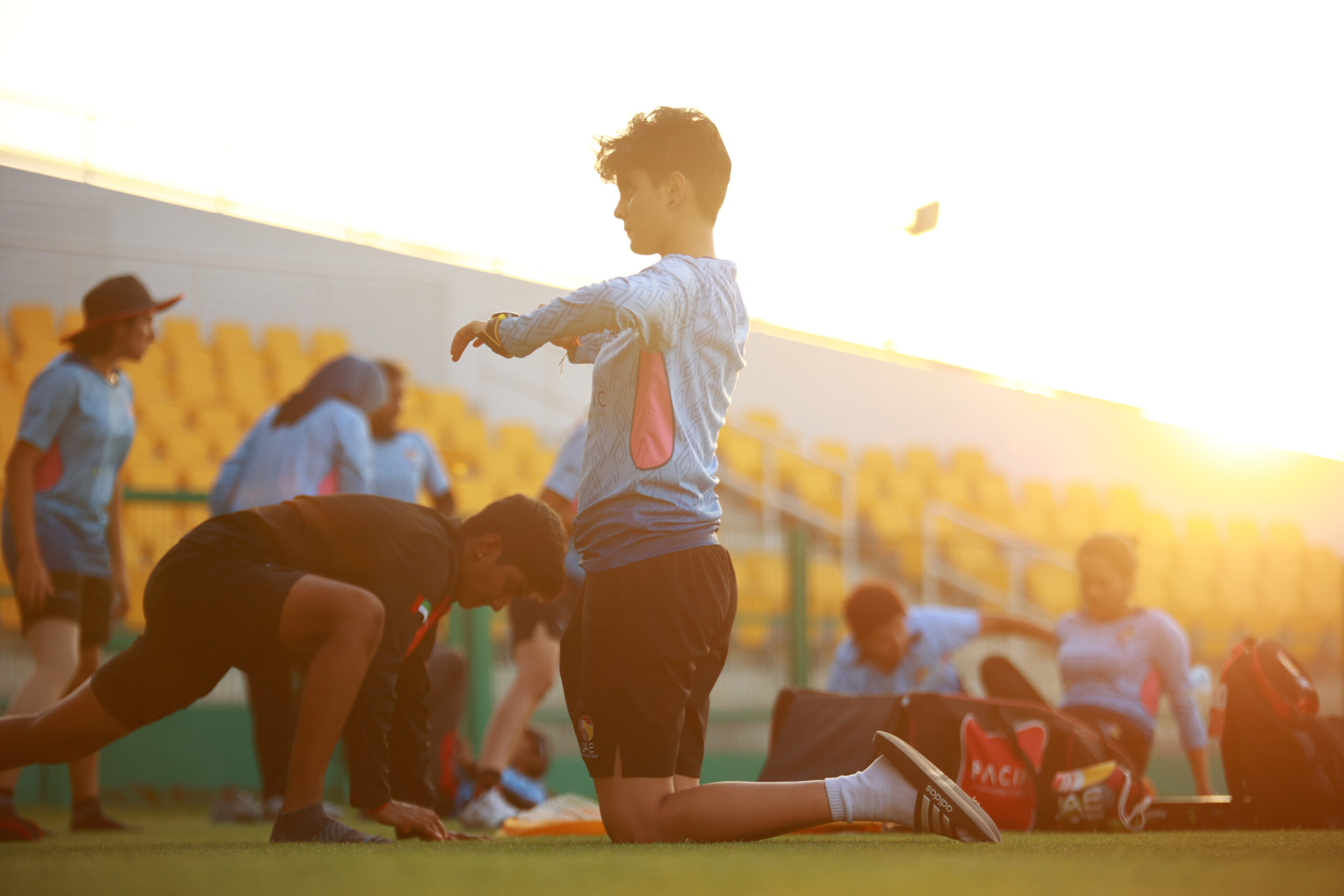 UAE cricket player performing dynamic knee-down stretches during a golden hour training session in Dubai