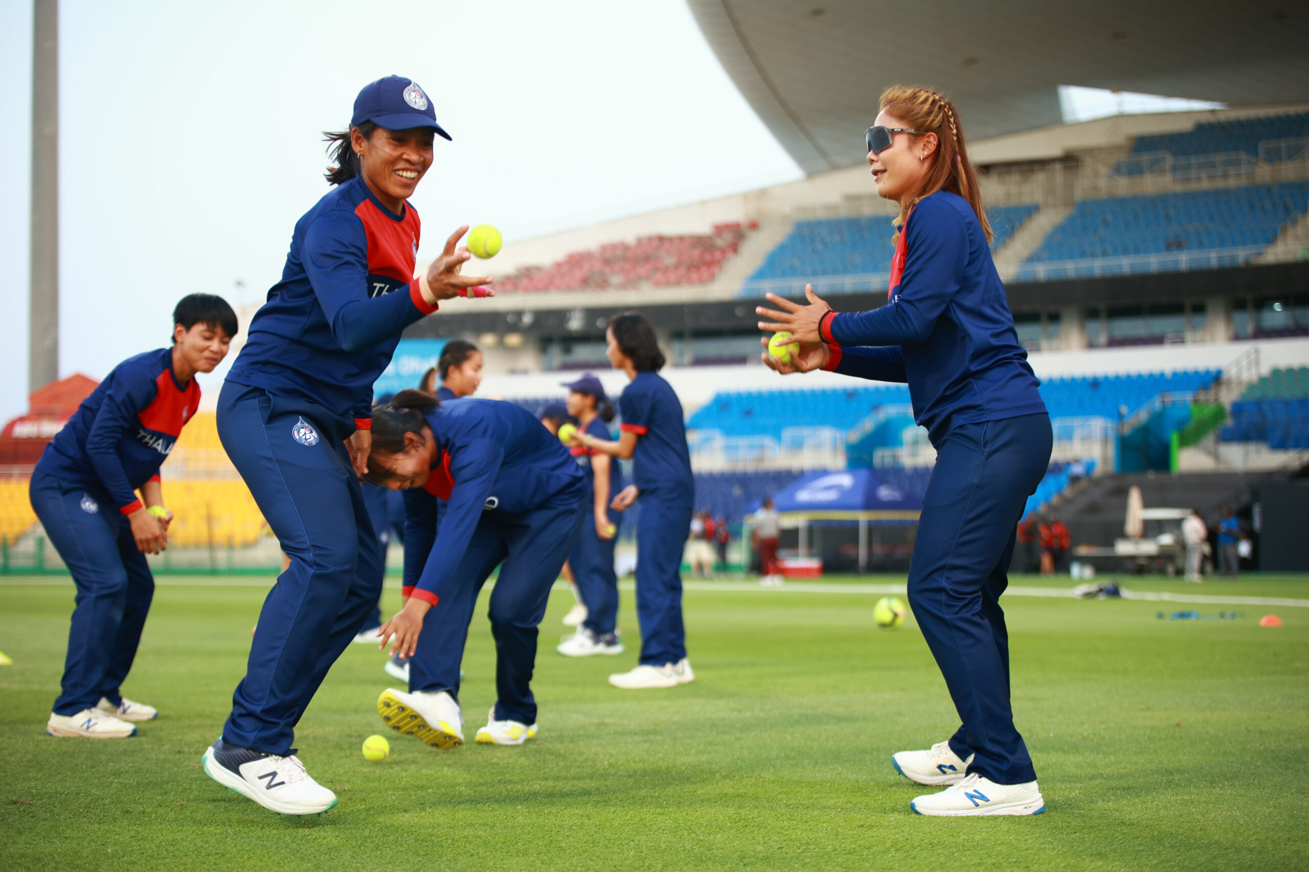 Thailand women’s national cricket team players practicing ball-handling drills at a cricket stadium in Dubai