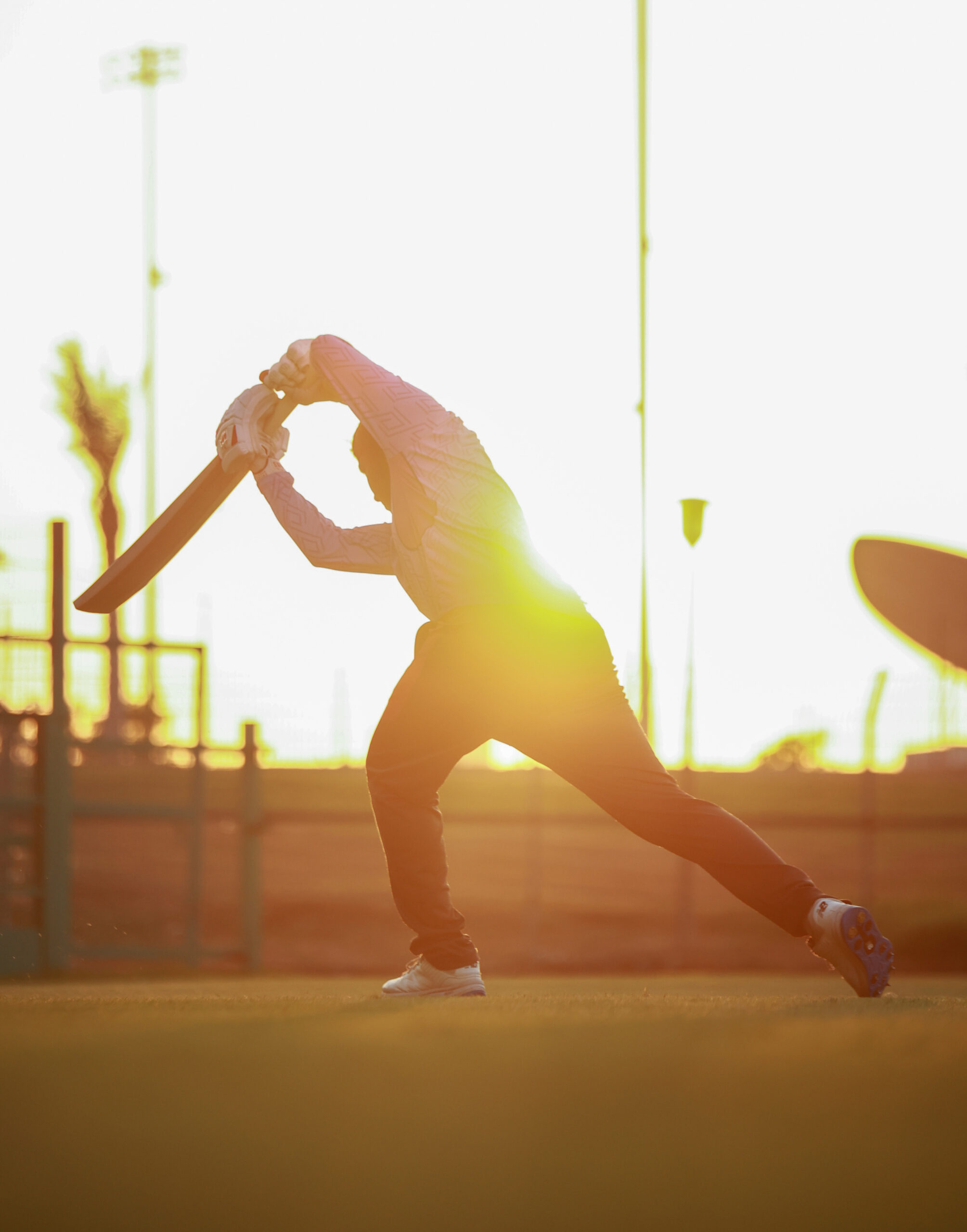 Professional female cricketer in a blue Bangladesh kit performing overhead mobility drills with a resistance band during warm-ups in a UAE stadium