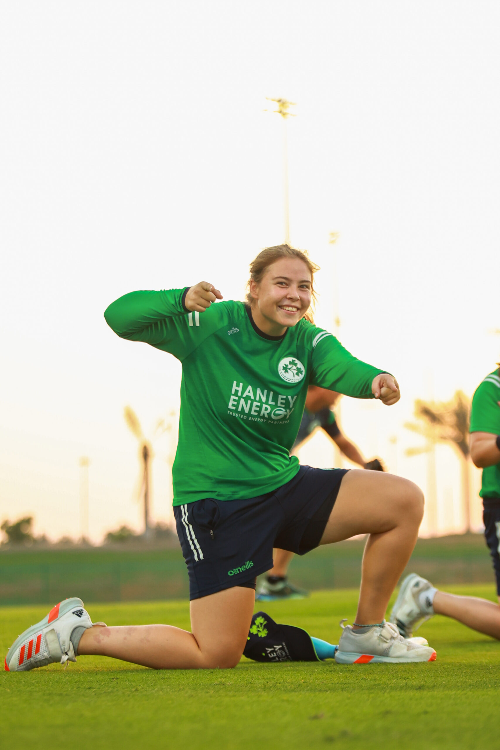 Professional female athlete in green Ireland jersey training at a Dubai sports facility during sunset.