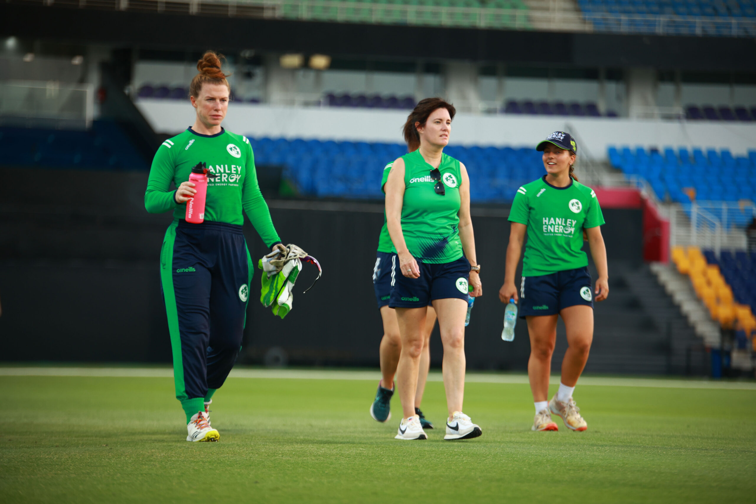 Zimbabwe women's cricket team celebrating on the field during a golden hour match in the UAE.