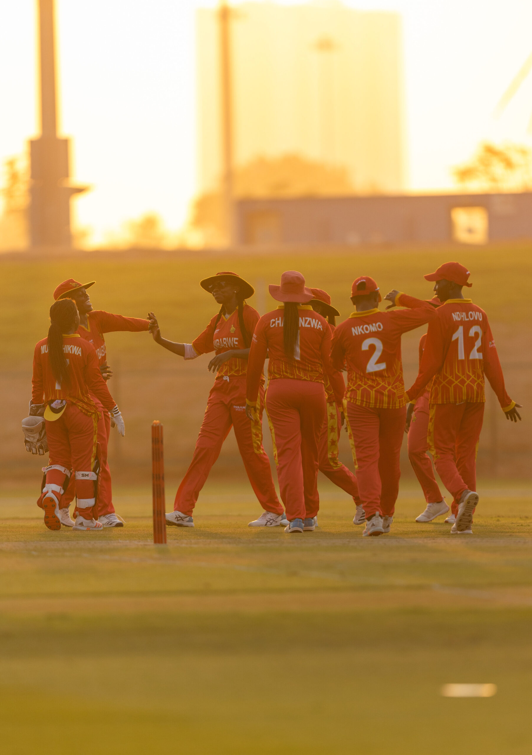 Ireland women’s cricketers walking across the pitch at a professional cricket stadium in Abu Dhabi.