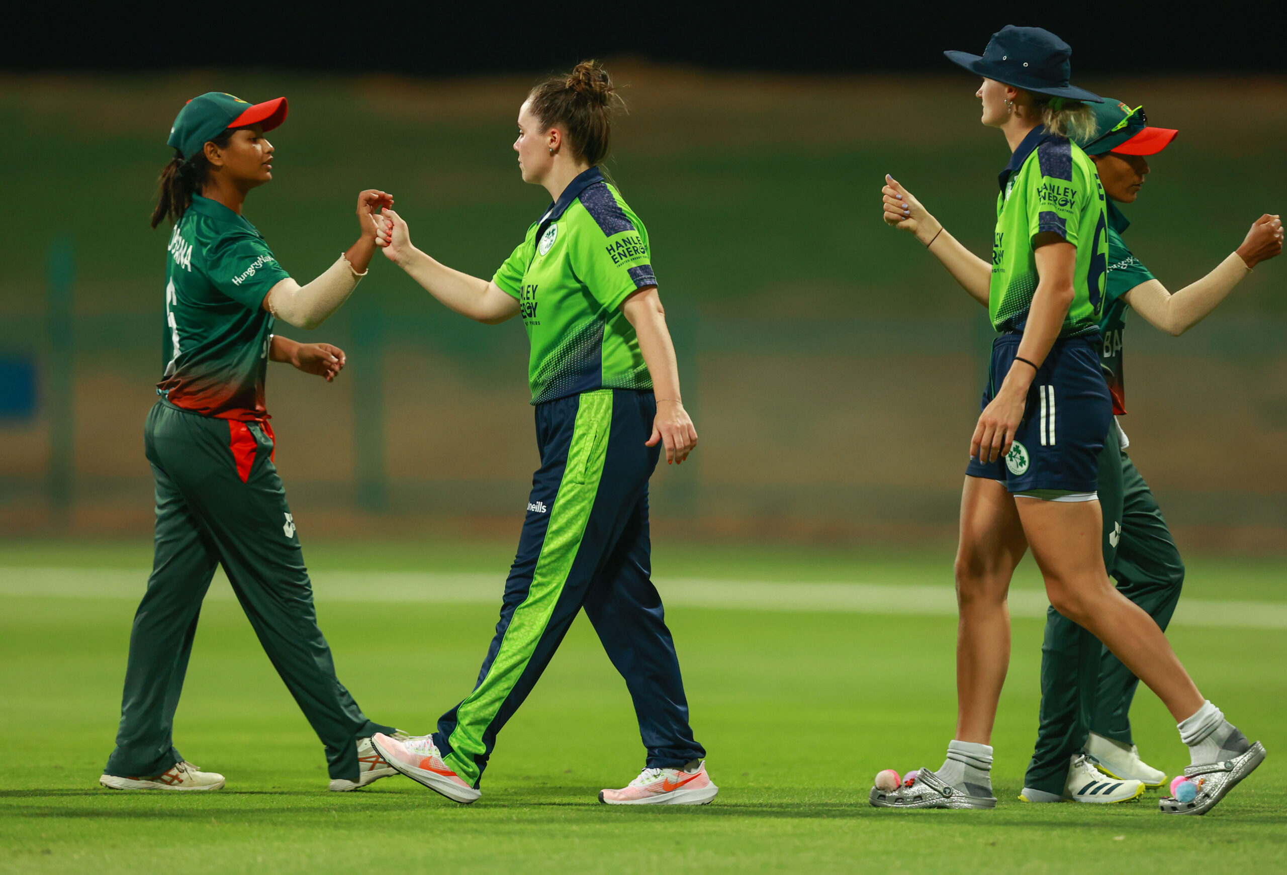 Ireland and Bangladesh women cricketers shaking hands and showing sportsmanship on the cricket field.