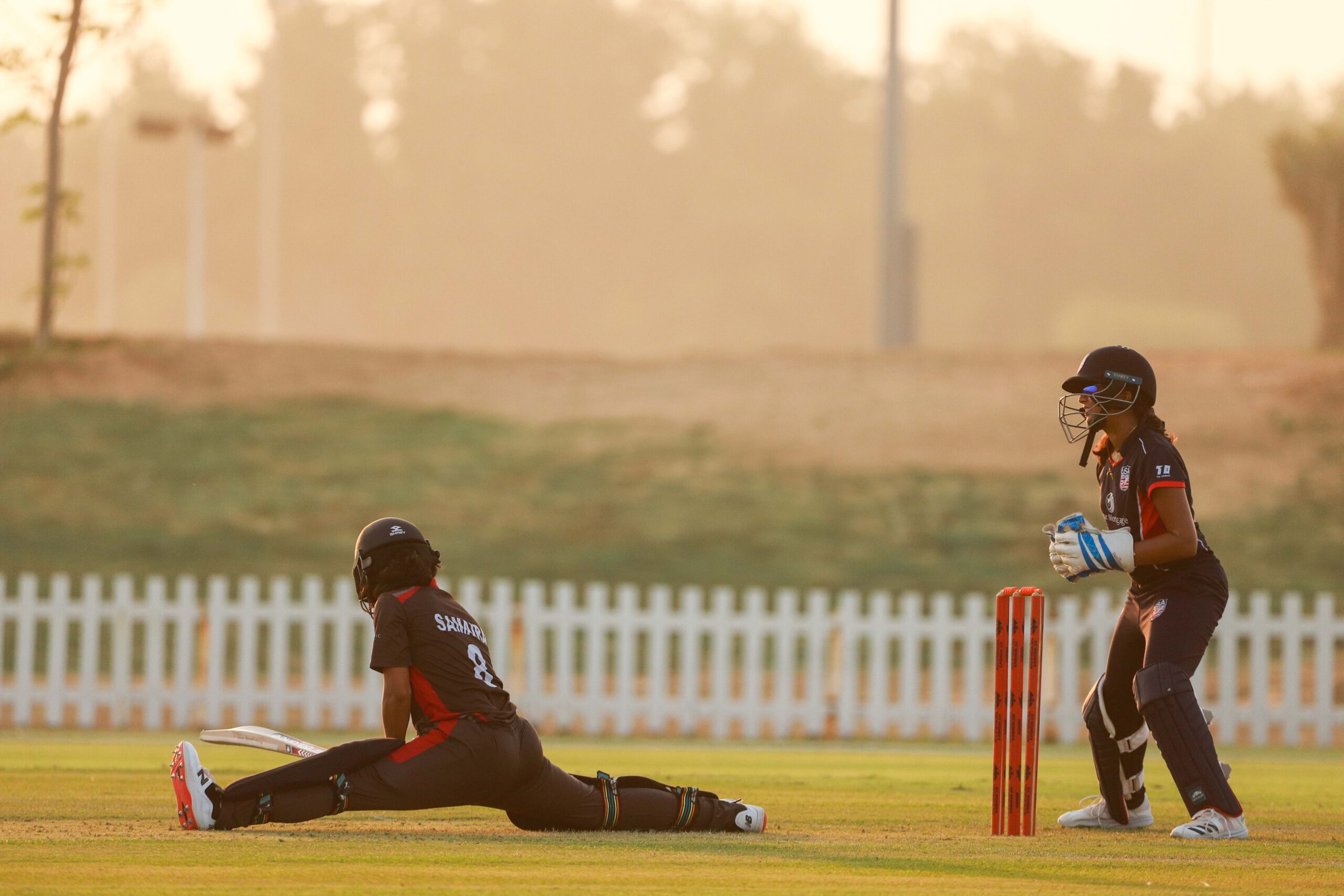 International women's cricket match at sunset in Dubai featuring UAE and USA national team players.